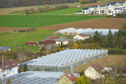 Greenhouses and rural buildings in landscape. Panoramic view of rural area with greenhouses, residential houses and farm buildings.