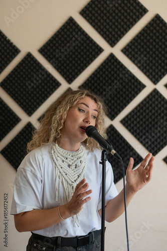 Caucasian woman singing into microphone in music studio. 