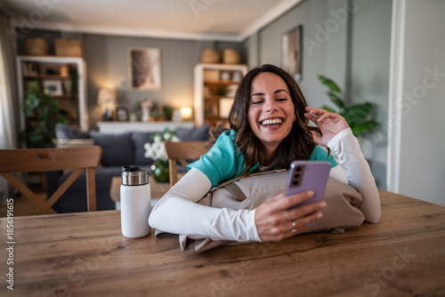 Woman laughing while communicating on smartphone at home