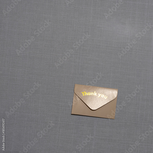 A small  envelope with “Thank you” embossed on it rests on a soft textured surface, symbolizing gratitude, elegance, simplicity, and thoughtful appreciation in a minimal scene.
