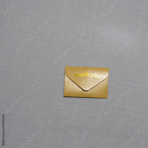 A small  envelope with “Thank you” embossed on it rests on a soft textured surface, symbolizing gratitude, elegance, simplicity, and thoughtful appreciation in a minimal scene.