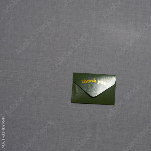A small  envelope with “Thank you” embossed on it rests on a soft textured surface, symbolizing gratitude, elegance, simplicity, and thoughtful appreciation in a minimal scene.
