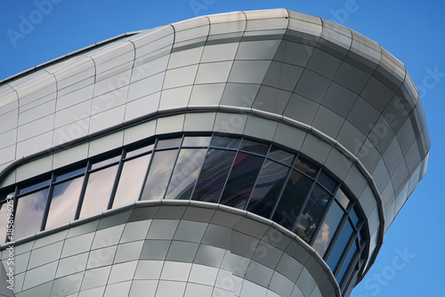 The metallic roof of a big, modern business building with windows.