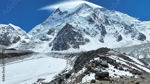 Majestic snow-covered mountains with glaciers and a blue sky above a rocky, snow landscape