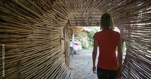 Woman walks through a pathway made of sticks and branches. 