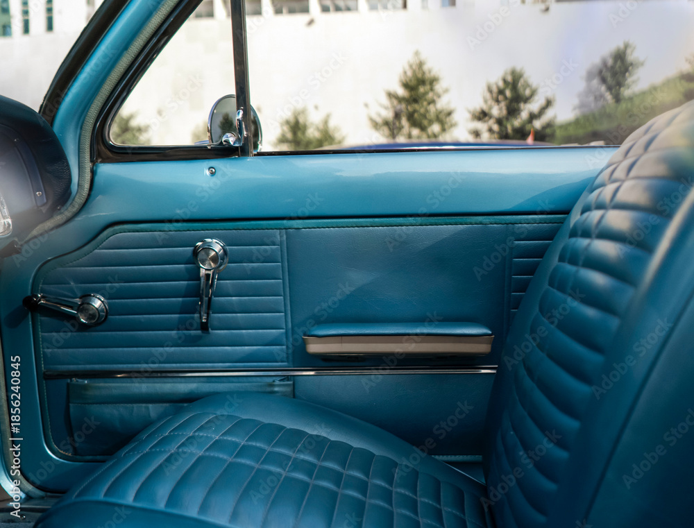 Obraz premium A classic car interior features blue seats and dash with a simple design under natural light