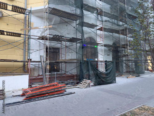 Workers prepare building materials at a construction site with scaffolding and tools in the evening
