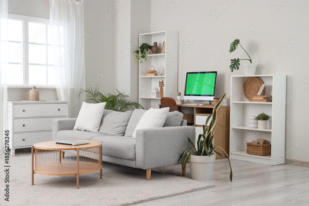 Fototapeta premium Modern computer with blank screen on table and laptop in living room