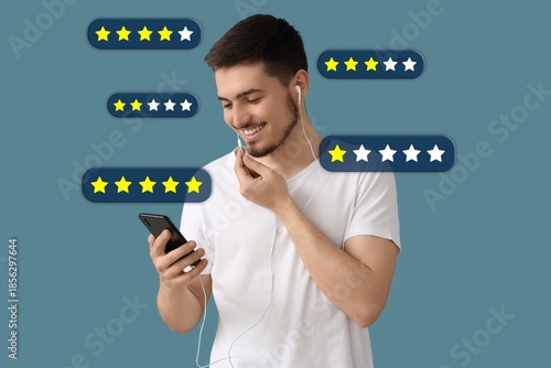 Young man with mobile phone and earphones on blue background. Rating concept