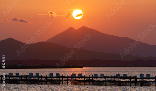 霞ヶ浦から望む夕暮れ時の筑波山と山頂に位置する太陽