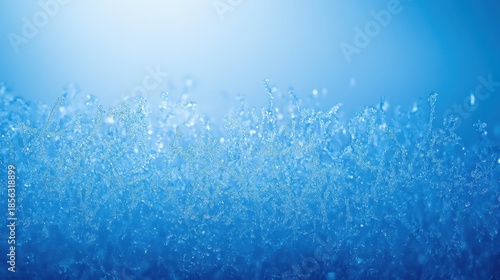 Delicate frost patterns forming on a cold glass surface with shimmering blue light