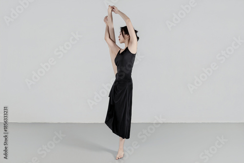 A beautiful girl wearing a black long dress is practicing dance in the dance studio