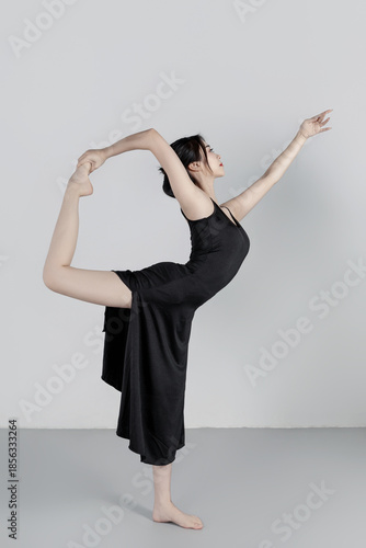 A beautiful girl wearing a black long dress is practicing dance in the dance studio