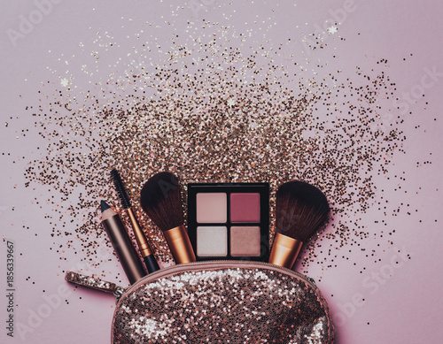 Sparkling makeup kit with brushes and eyeshadow on pink background