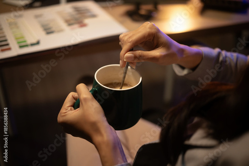 Photos Close-up of hands stirring coffee in a mug, capturing a caffeine boost during a