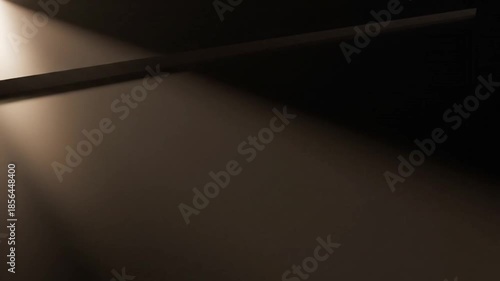 A dark room with a beam of light shining through a gap in the wall onto a floor with a dramatic and mysterious mood.