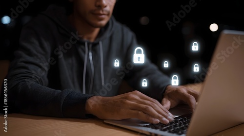 Wallpaper Mural A person in a hoodie working on a laptop at night surrounded by glowing lock icons symbolizing digital security and privacy protection Torontodigital.ca