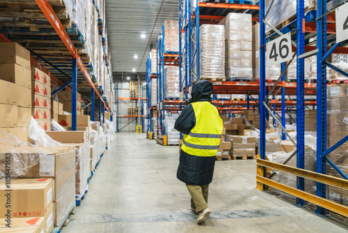 Canvastavla Worker wearing a winter jacket and high visibility vest, walking along an aisle