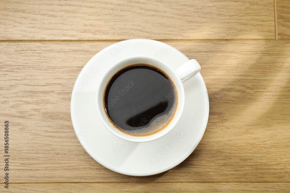 Obraz premium Aromatic coffee in cup on wooden table, top view