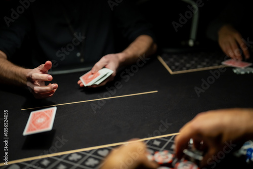 Professional casino poker dealer dealing playing cards to players at felt table, capturing regulated card distribution process during live gambling operations