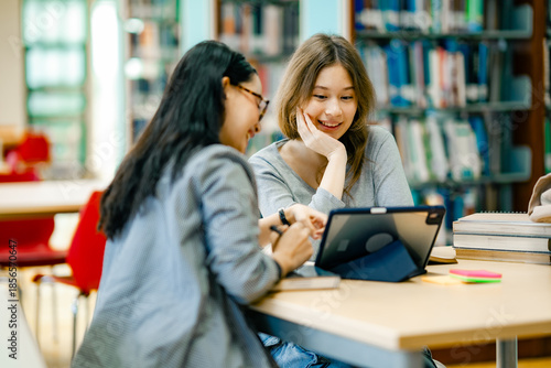 Canvas Print Female students learning through tablet at library with books representing blend