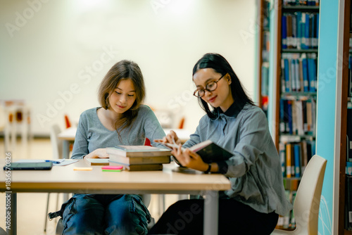 Tableau sur toile One on one tutoring session with tutor explaining lesson from textbook at library focused mentoring