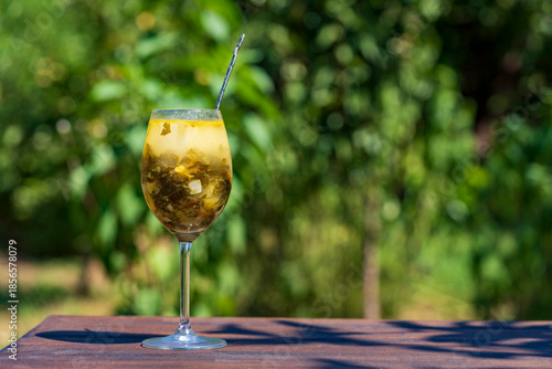 Summer green sorrel soup in a wine glass on nature background, closeup, copy space. Soup made from broth, sorrel leaves, spinach, boiled eggs, potato