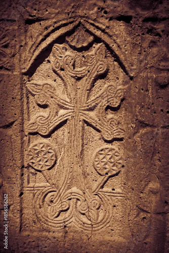 Khachkar - medieval Armenian headstone bearing carved cross, life scenes or decorative interlaces and botanical motifs. Close up sepia toned image