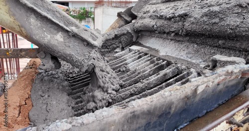 close up of wet concrete pouring from a mixer chute into a pump hopper.