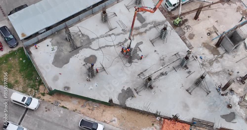 Aerial view of workers pouring concrete into a column formwork.
