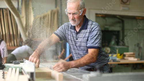 Senior carpenter cutting wood creating sawdust in workshop