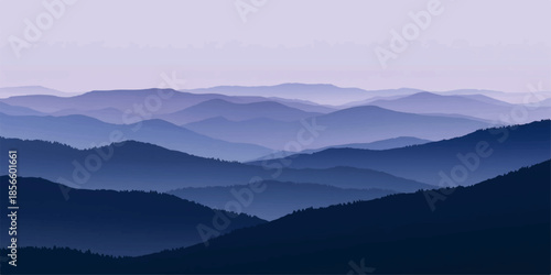 A misty blue mountain range at dawn with a forest valley under a soft morning sky where sunlight breaks through the fog and clouds over the peaks.