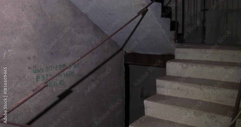a slow, descent down a rugged concrete stairwell within an ...