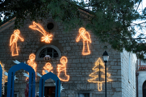 Church facade decorated with illuminated Christmas figures depicting angels, the nativity scene, and a comet star