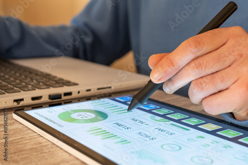 Business professional using a digital tablet and stylus to analyze carbon emissions data, financial growth, and environmental, social, and governance metrics for sustainable development