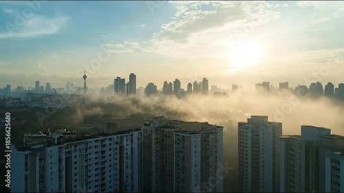 Foggy cityscape with cell tower and high-rise buildings at sunrise
