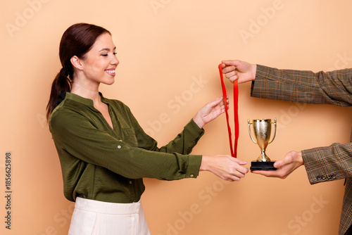 Young businesswoman receives award medal during office celebration with smiling focus on trophy
