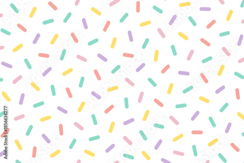 Colorful sprinkles scattered on a white background create a playful and fun pattern for design and decoration purposes