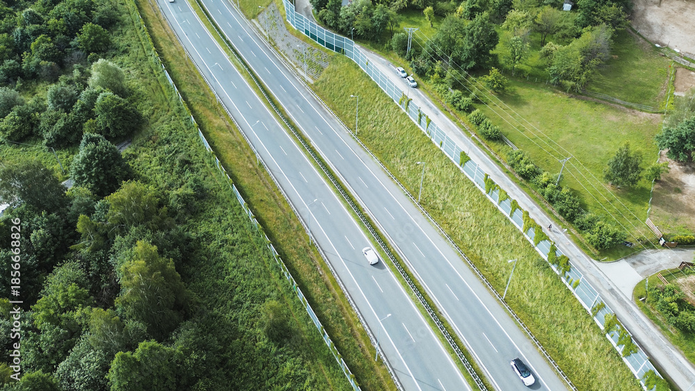 Fototapeta premium Trucks and Cars on Road by Green Barrier