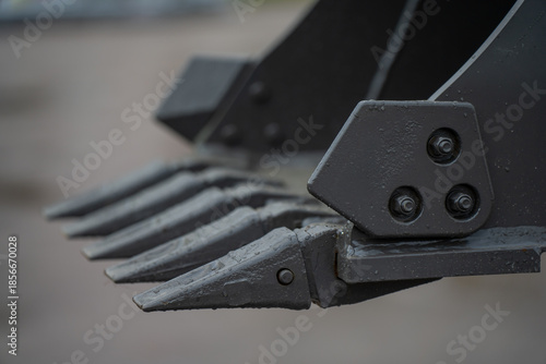 Construction excavator digging attachment featuring steel bucket teeth and connector plate, focused on earthmoving machinery engineering and durability