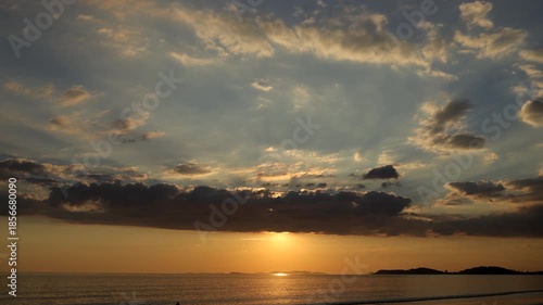 Time-lapse of the sun emerging from behind clouds before slowly setting over the sea.