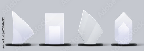 Glass trophy set with elegant crystal plates. Transparent award collection with unique glass shapes on dark pedestals designs for business or sport recognition ceremonies.