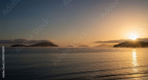Serene sunrise over misty islands and calm sea