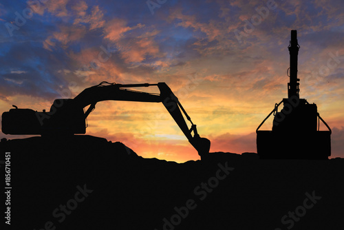 Crawler excavators silhouette are digging the soil in the construction site. With blue sky and clouds of on sunset background