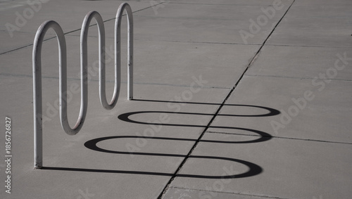 curved or wavy shadow lines on the pavement of a bicycle rack or curved installation on the sidewalk outdoors curved shadow lines horizontal backdrop background or wallpaper