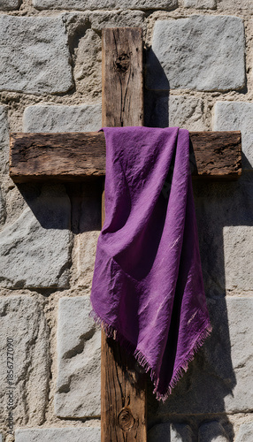 Weathered wooden cross draped with purple cloth on stone wall - Concept of Lent  
