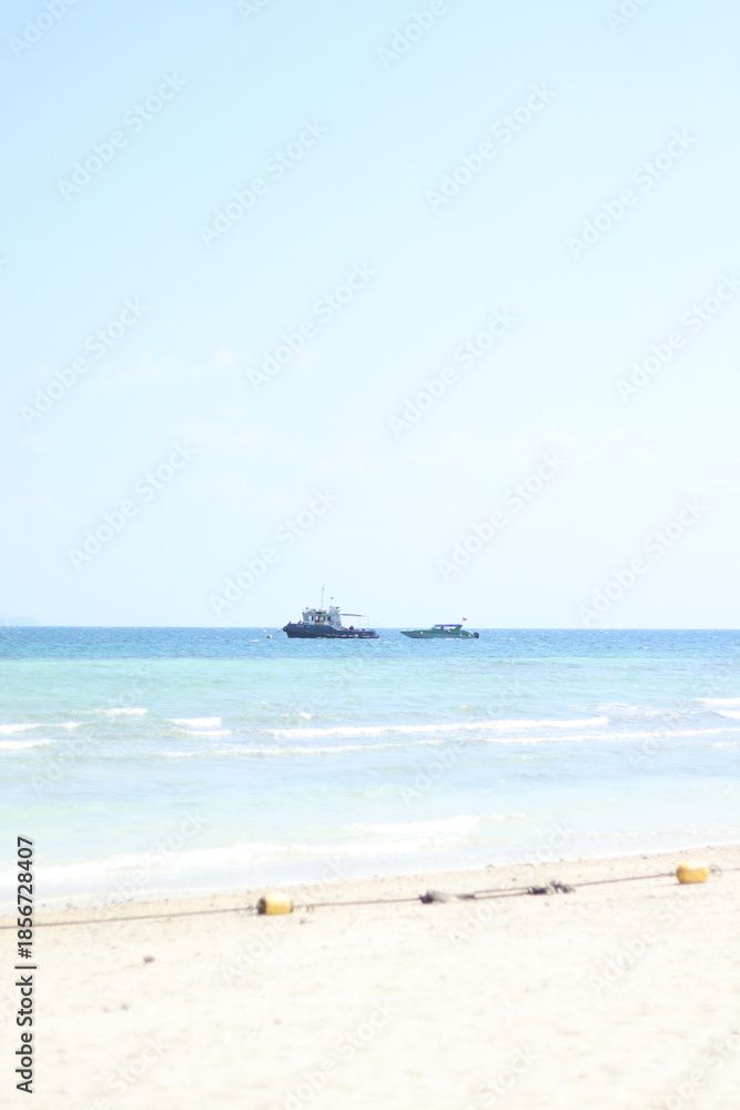 Obraz premium Small motorboats float on clear blue water near a sunny sandy beach shore
