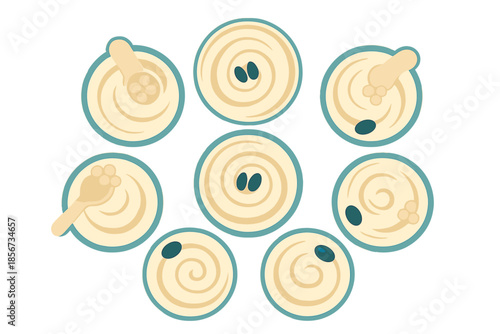 Top view of eight bowls of hummus with toppings