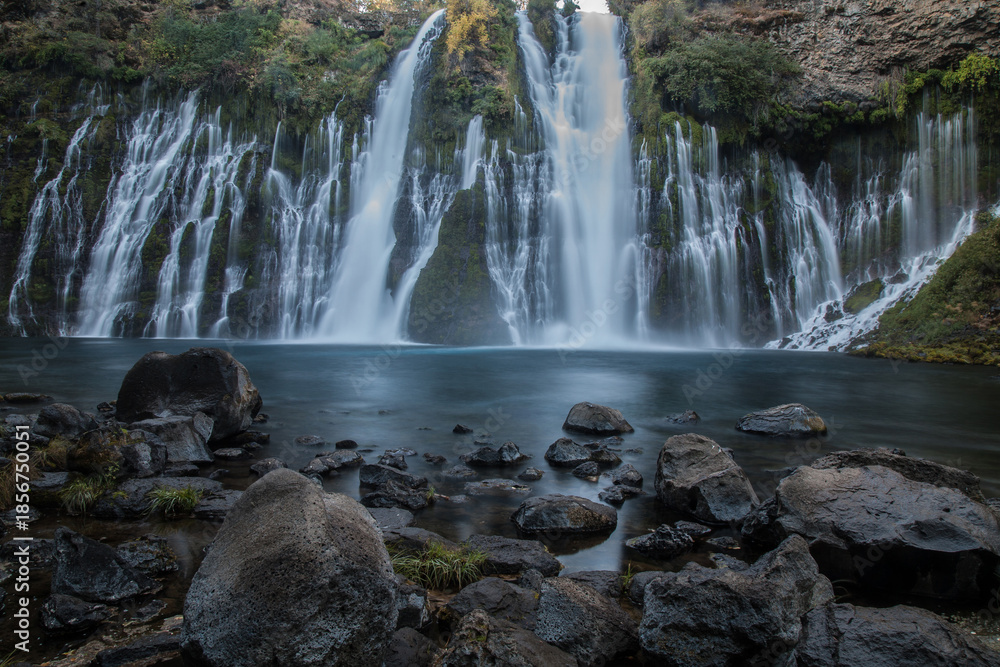 Fototapeta premium Burney Falls in early dawn light with stones in the foreground.