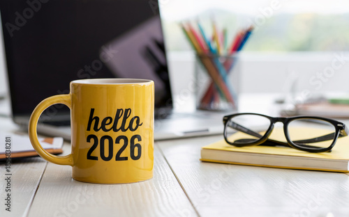 Yellow Coffee Mug with Hello 2026 Text on Office Desk for New Year Concept